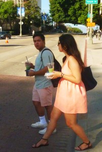 hispanic man and woman carrying food and coffee drinks start to cross the street head ing to Grand Park in downtown LA