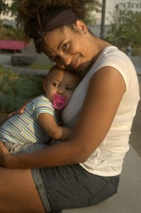 africian american mom and son cuddle while sitting in park nearLA city hall