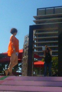 Asain female poses in bright orange blouse poses for photo in theater area above Grand Parkcourt 