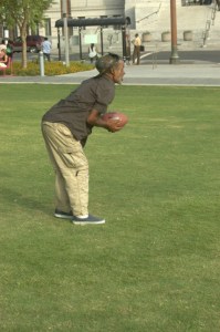 older Africian Amercian catches football in park