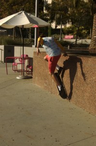 teen boy does trick against wall on his skateboard,