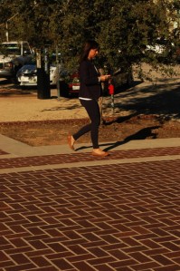 young attractive hispanic woman walks away from Pasadena city hall with her smart phone