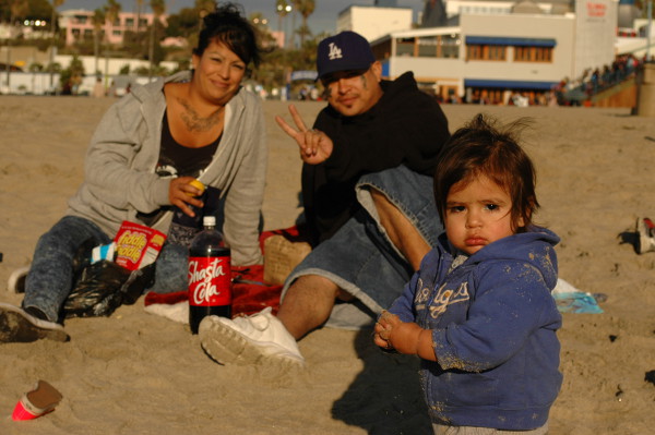 hispanic boy iwht his parents plays in the sand Santa Monica CA