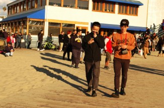 2 youinger man aiwth Ipjhones walk at Santa Monica beach black friday 2015