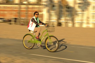 Asain female rides bike at beach, with sun glasses on
