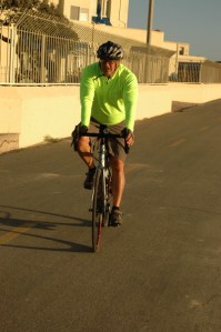 middle ages man in yellow shirt with helmet and sunglasses bikes at the beach