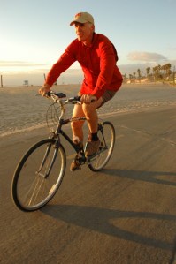 mature man in red rides bike at Huntington Beach, CA