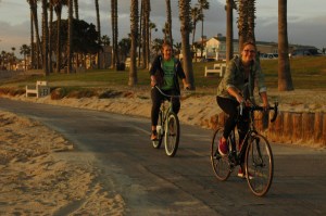 2 happy females in colorful attire run bikes