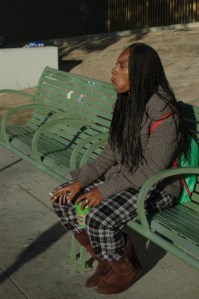 African American female sits on bench with coffee