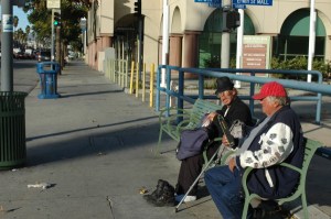 2 older colorful men sit on bench