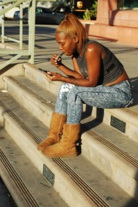 pretty 20 something looks at Ipone and smoles an e cig