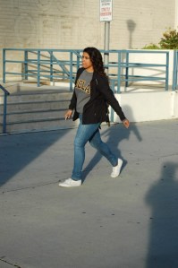 Hispanic teen with UCLA suit stroll down street near goverment buildings