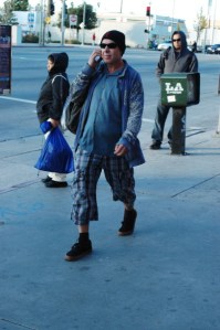 man walks on Van Nuys Bvld with android phone & pants that are too short and colorful