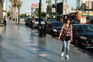 young & attractive female walks past the stars on hollywood Bvld