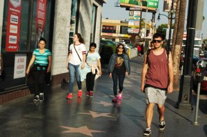 several young people walk past stars on Hollywood Blvd