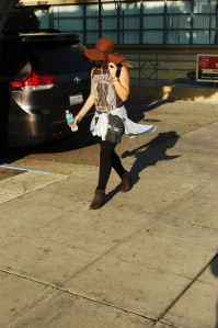 young female in large hat walks down Hollywood Bvld