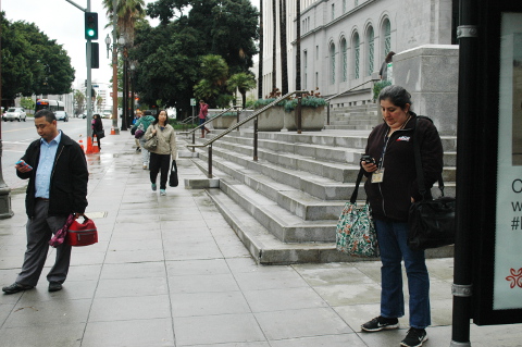 man & woman stnnd waiting for bus Los Angeles CA 4/8/16 rainy evening