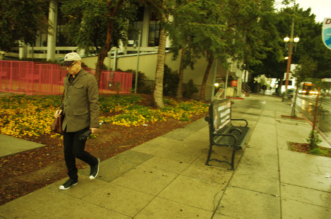 young man walks downtown LA, CA after rain shower