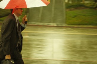lawyer caries case & umbrella in rain