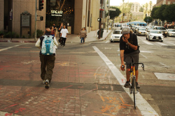 man on bike and others cross downtown St