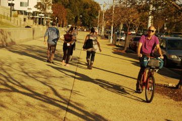 older guy bikes while others walk