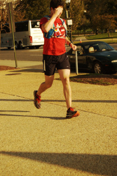 man in red shirt & cap jogs